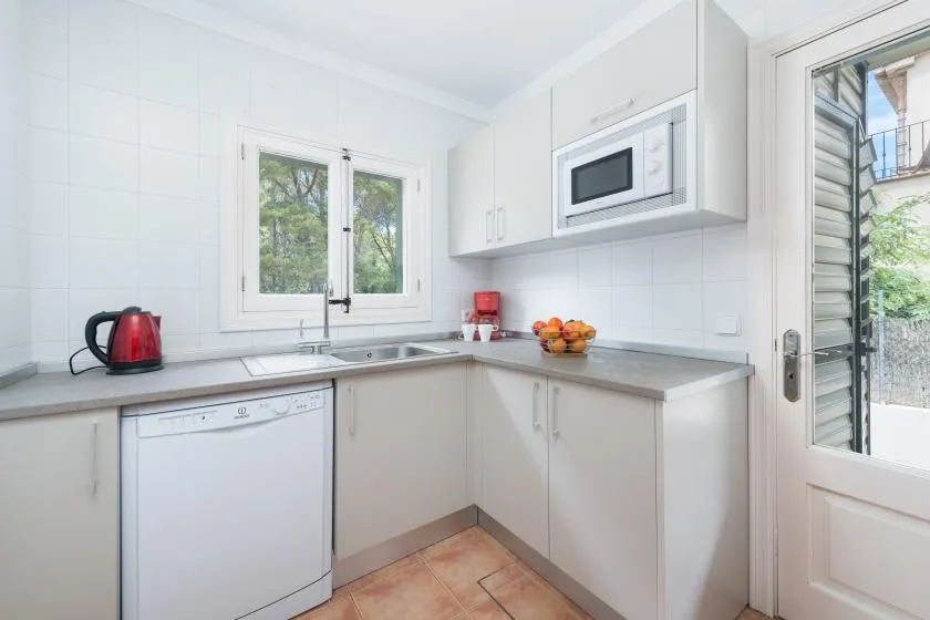 A compact white kitchen with a countertop, sink, and built-in appliances.