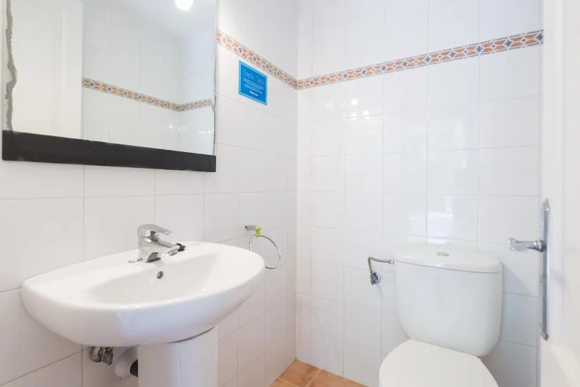 A tiled bathroom with a wall-mounted sink and toilet.