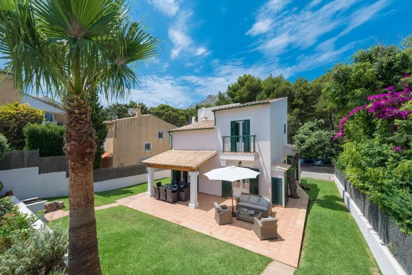 Una casa moderna con patio de baldosas, asientos al aire libre y césped.
