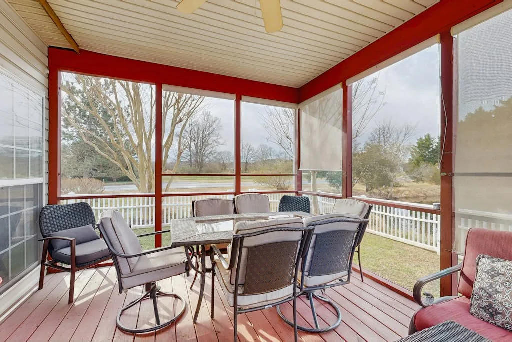 A screened-in porch with outdoor seating and a dining table.