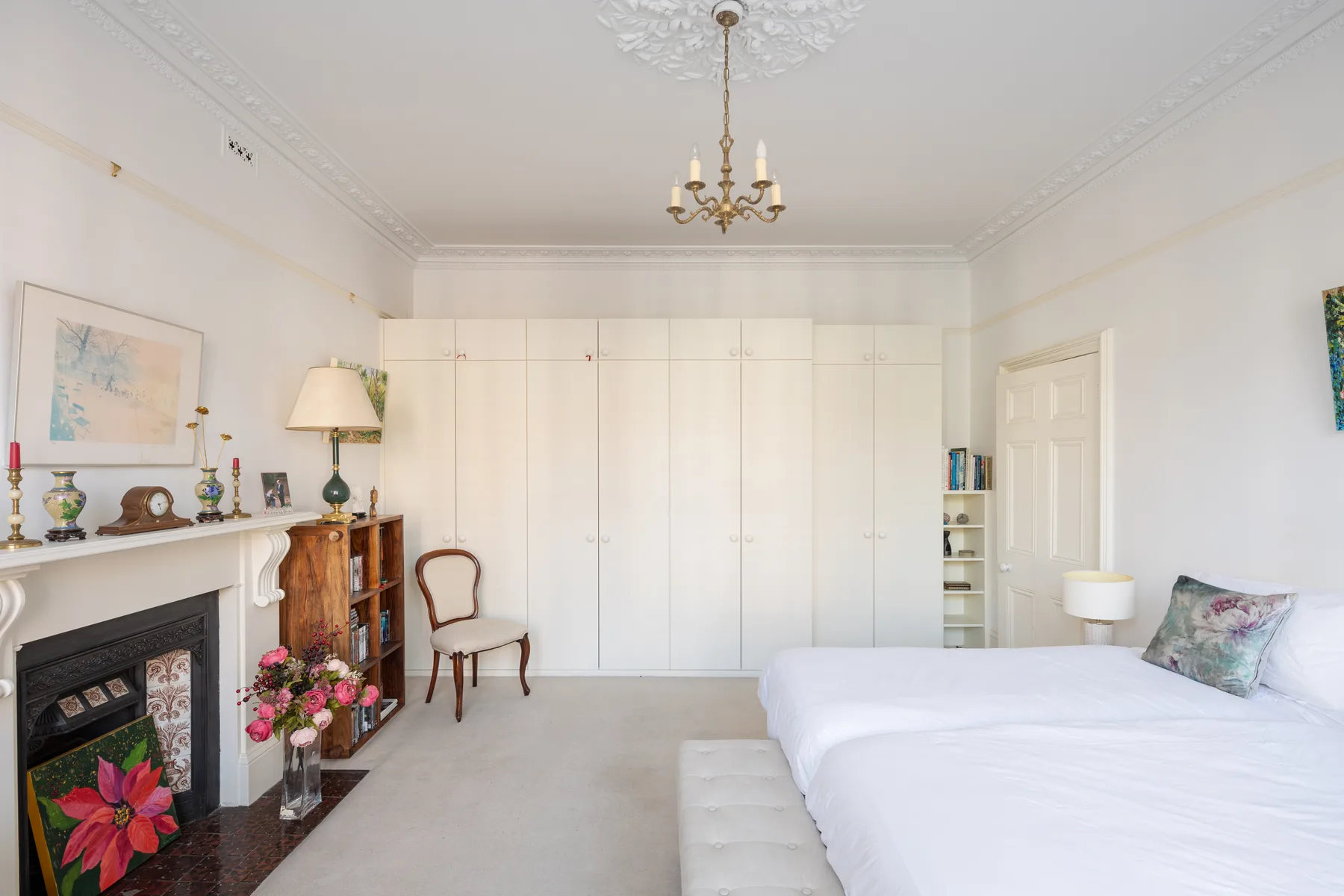 A bright bedroom with a large bed and built-in wardrobes.