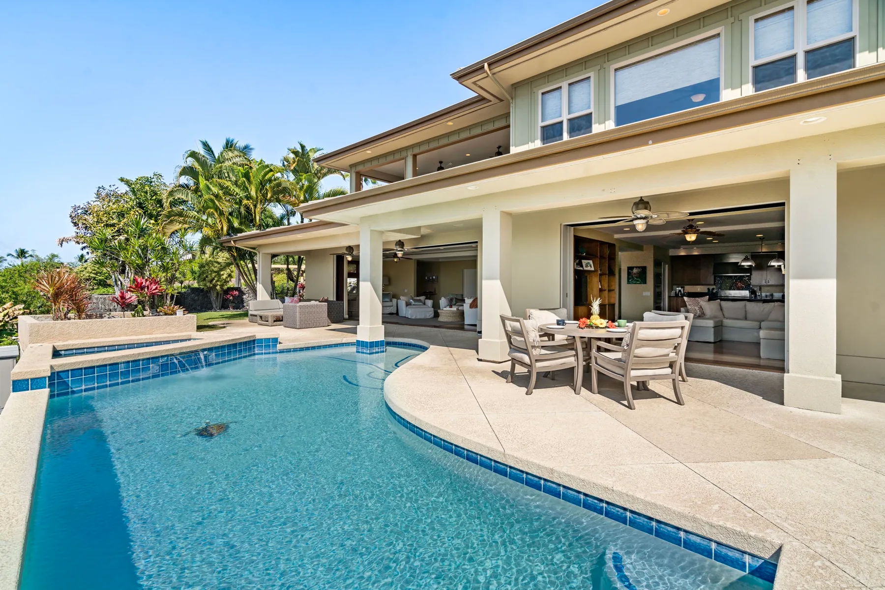 A swimming pool beside a covered patio with outdoor seating.