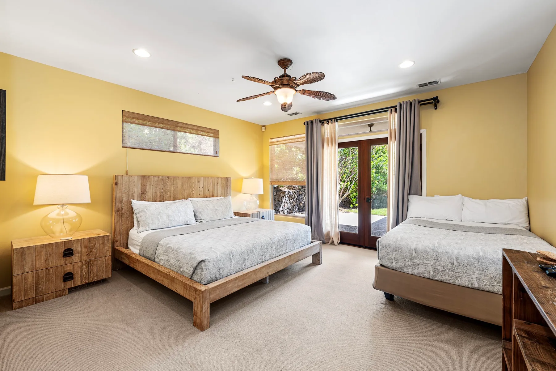 A bedroom with two beds, bedside tables, and glass doors opening to a patio.