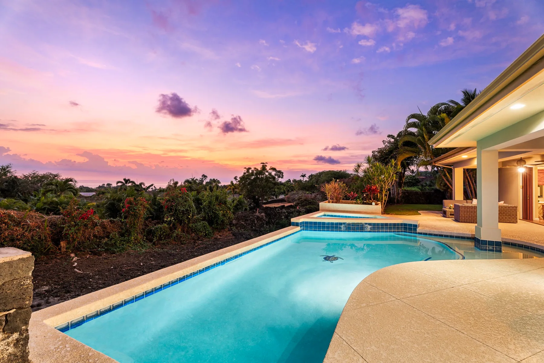 Una piscina al aire libre junto a un patio cubierto al atardecer.