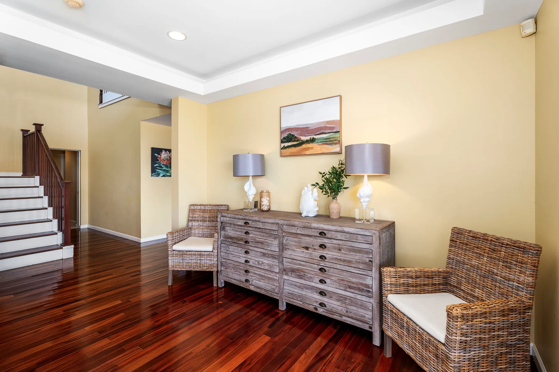 A furnished sitting area with wicker seating, a wooden dresser, and framed wall art.