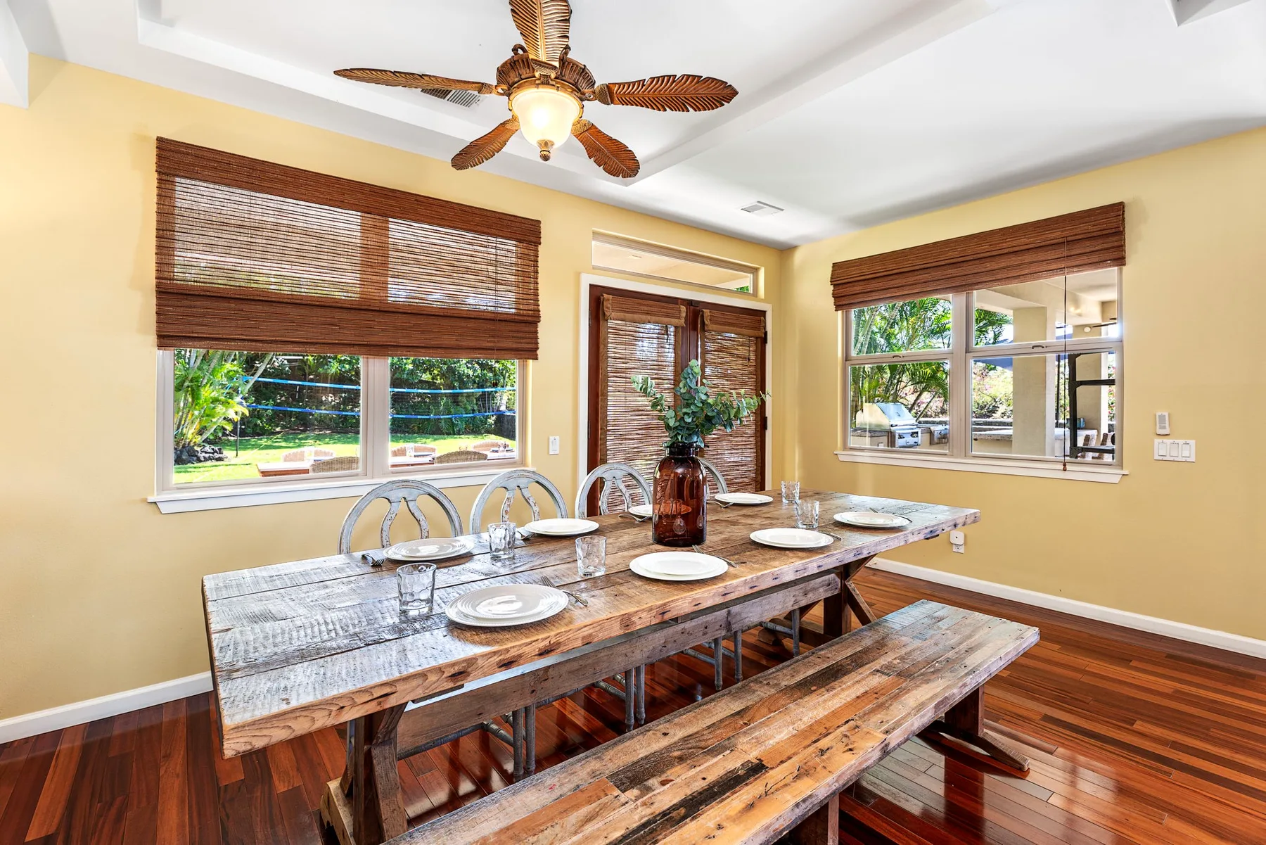 A dining area with a long wooden table beneath a ceiling fan.