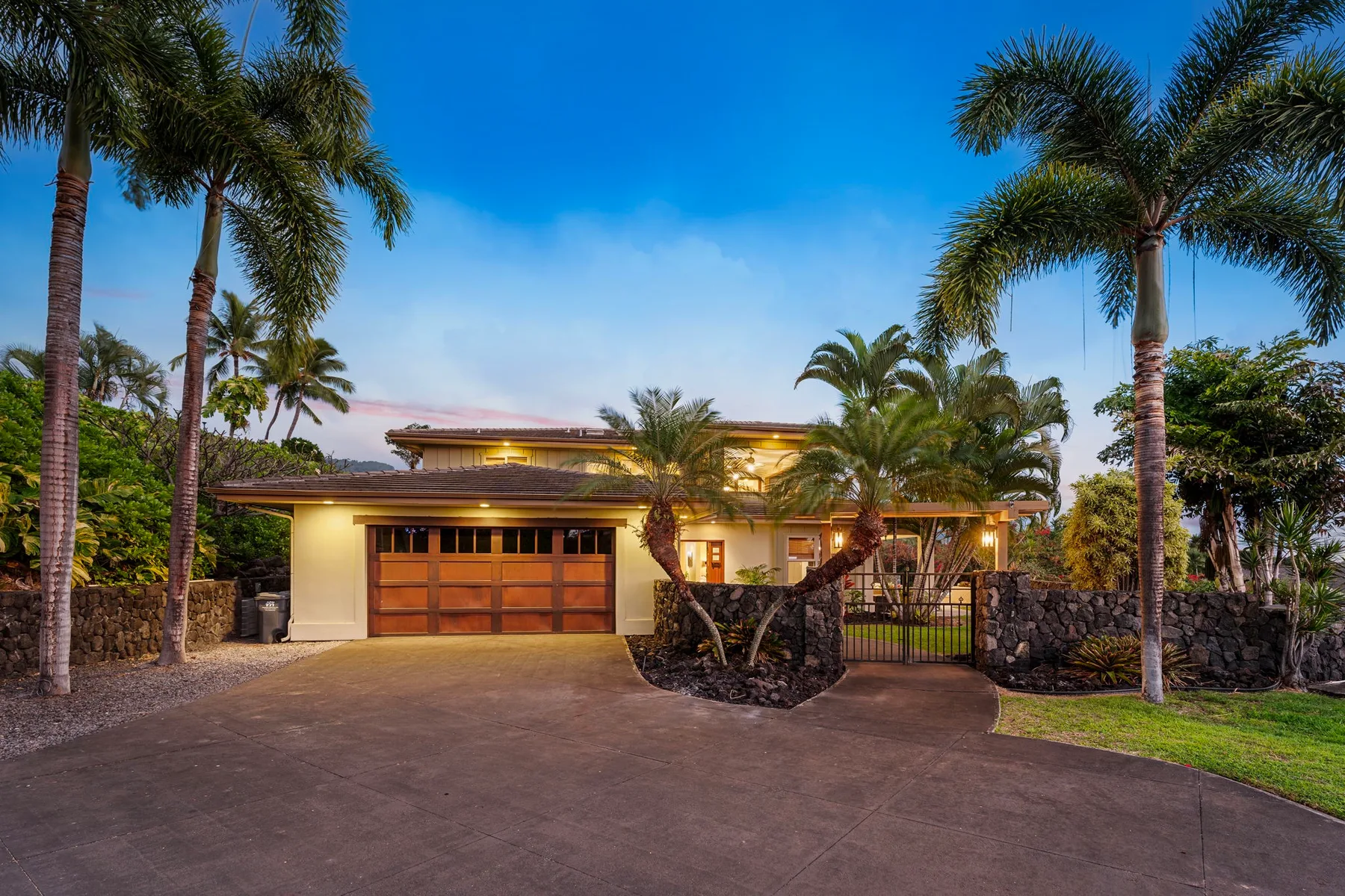A house exterior with a driveway, palm trees, and a garage.