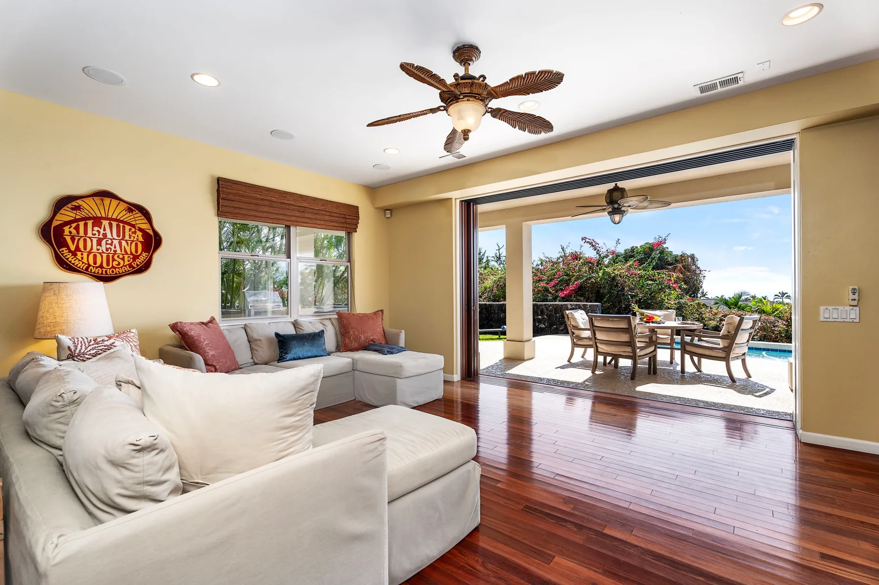 A living room opens onto a patio with outdoor seating and greenery.