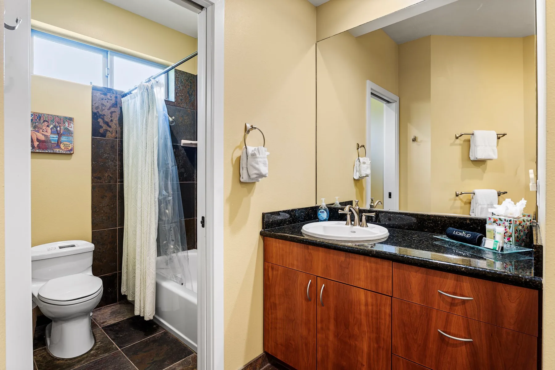 A bathroom with a sink vanity and a shower behind a curtain.