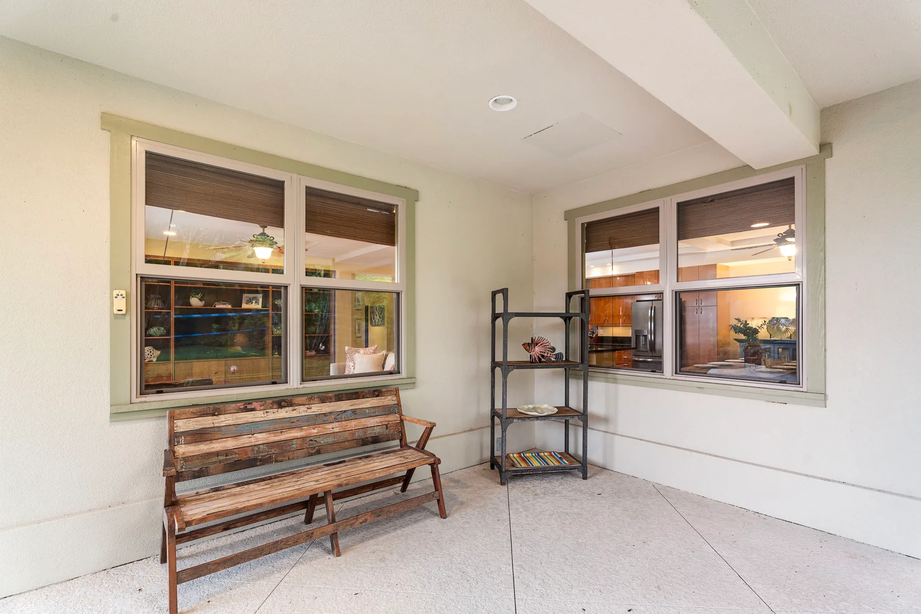 A covered patio with a wooden bench and a metal shelving unit.