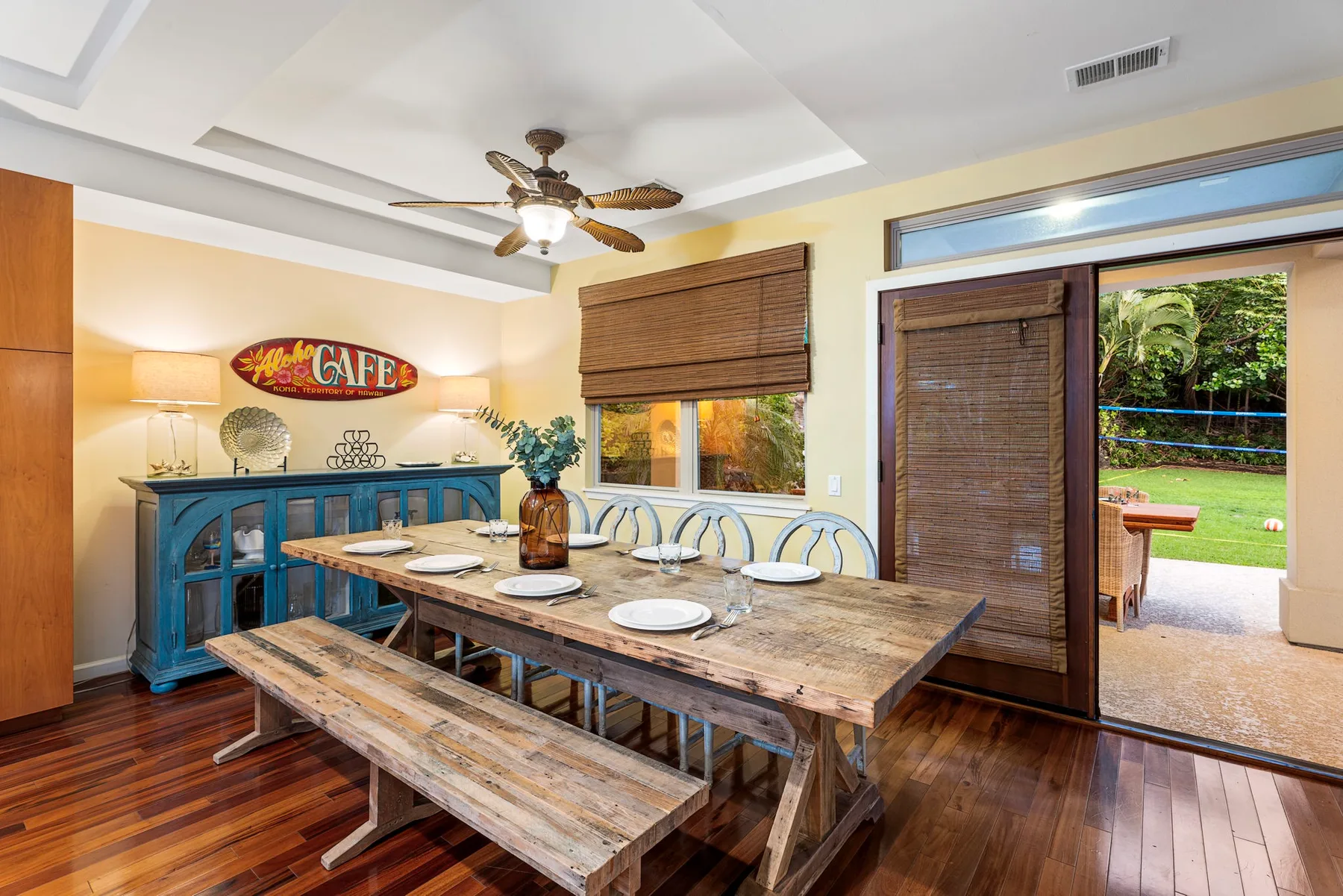 A dining area with a long wooden table and blue cabinet beside a glass door.