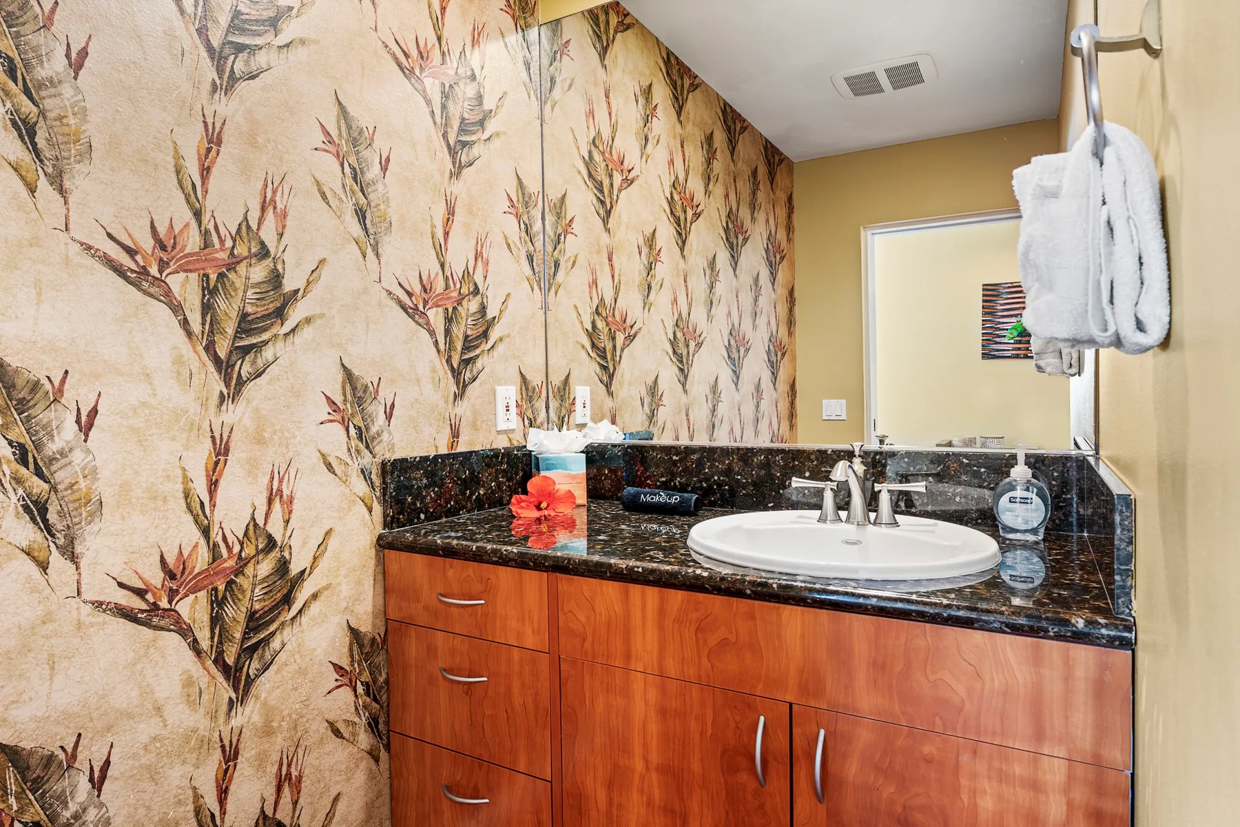 A bathroom vanity with a sink and patterned wallpaper.