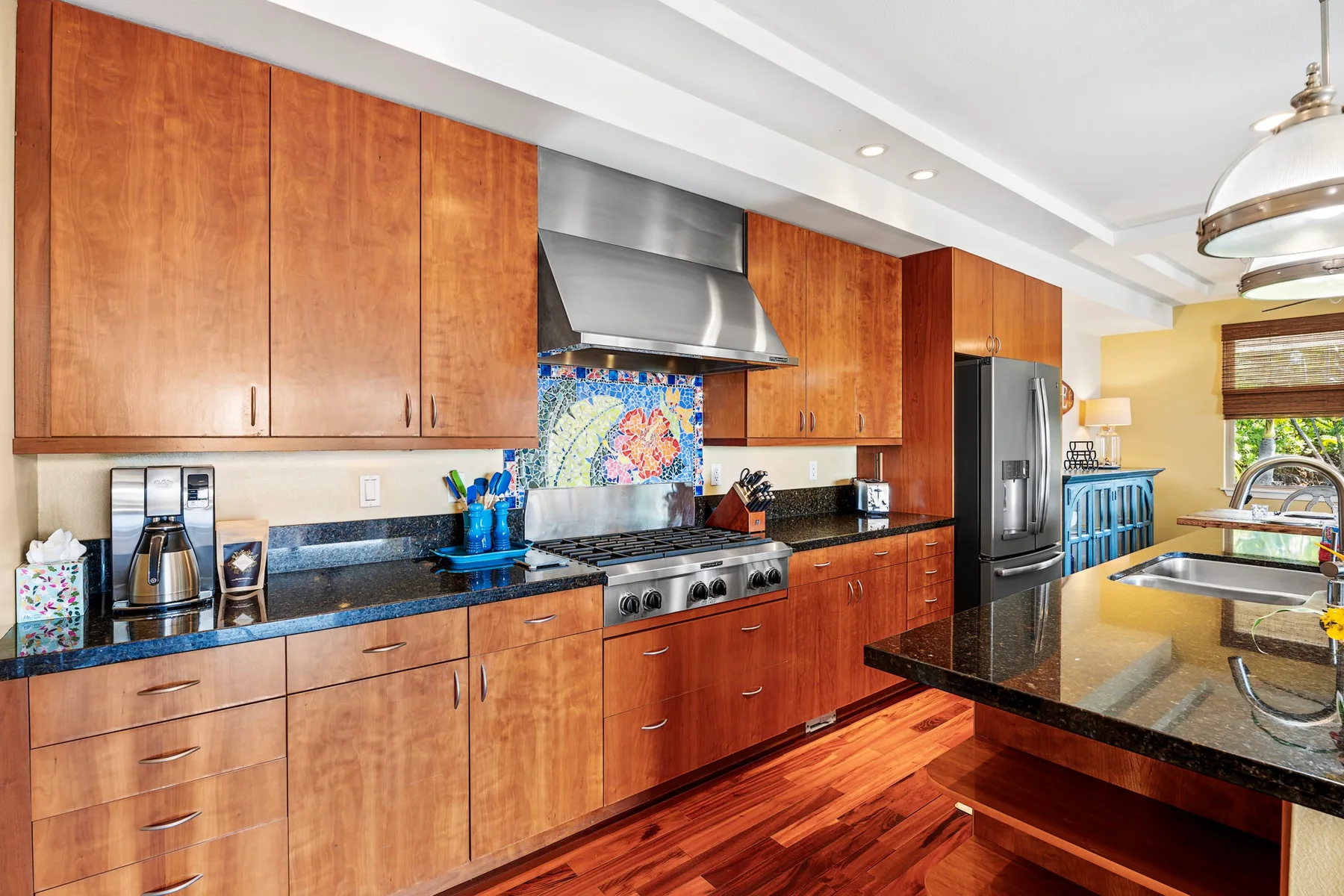 A kitchen with wood cabinets, stainless steel appliances, and dark countertops.