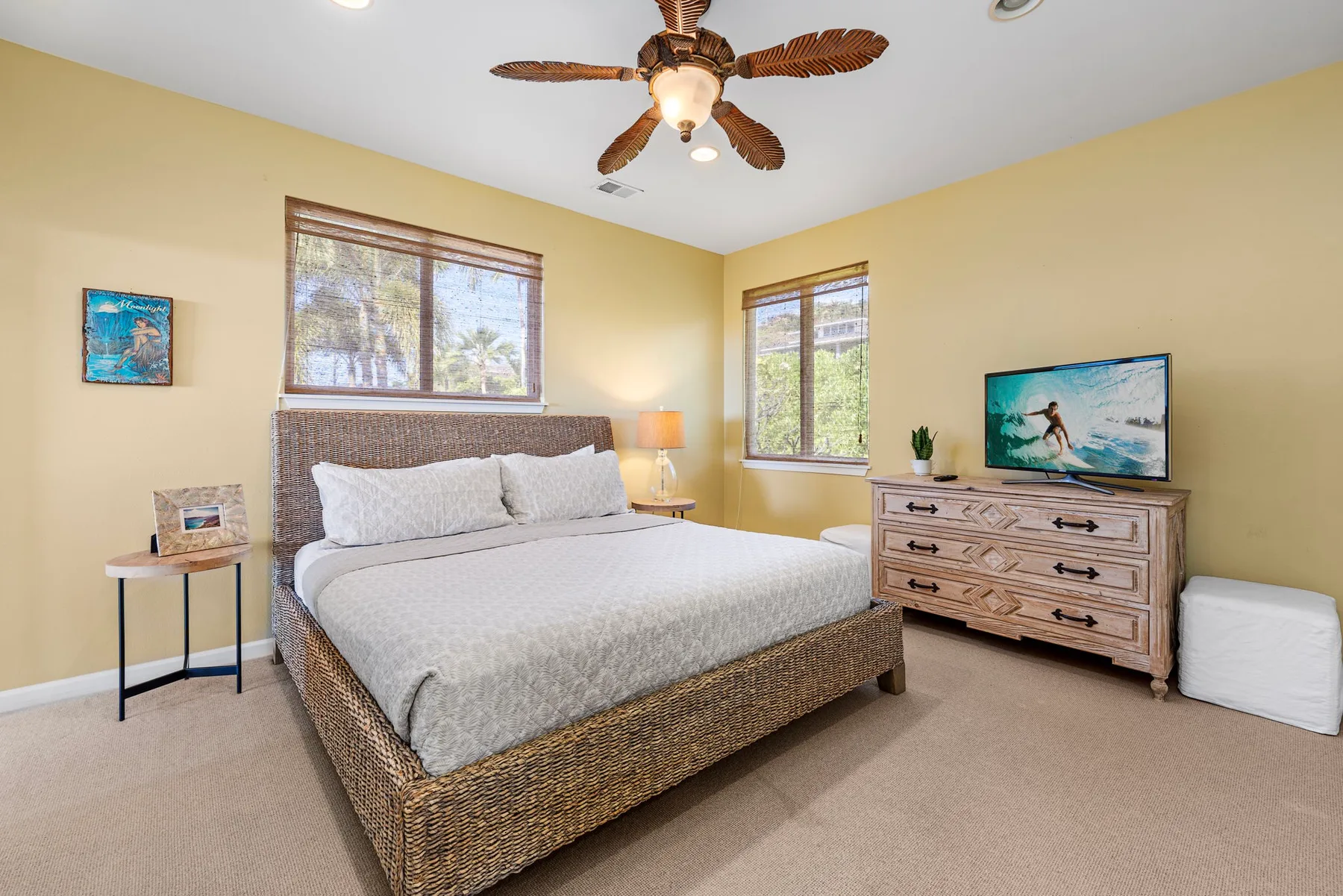 A bedroom with a large bed, a dresser, and two windows.