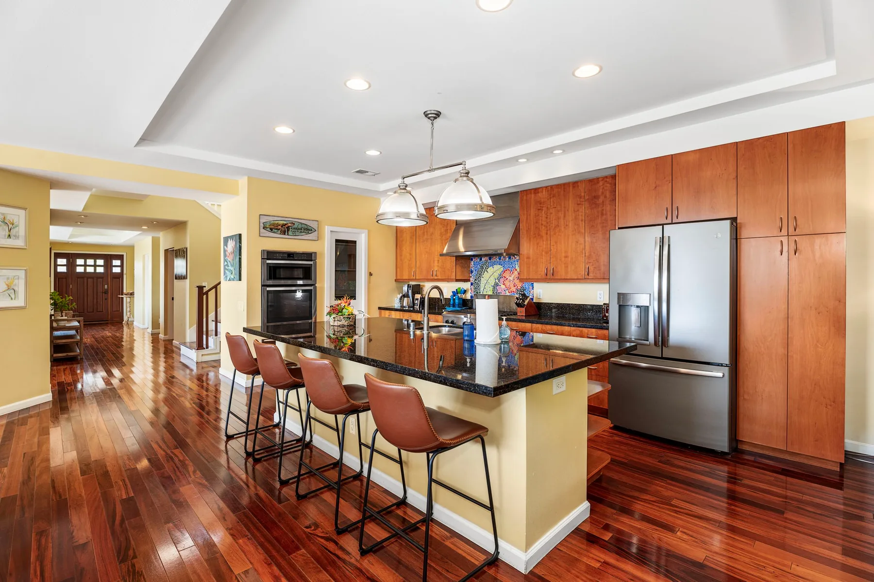 An open kitchen with a long island, bar seating, and wood cabinets.