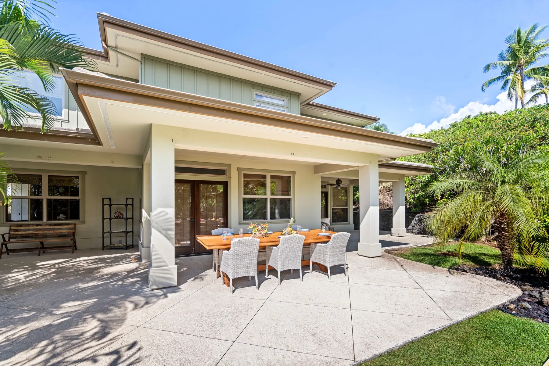Exterior patio with a dining table and seating beneath a covered area.