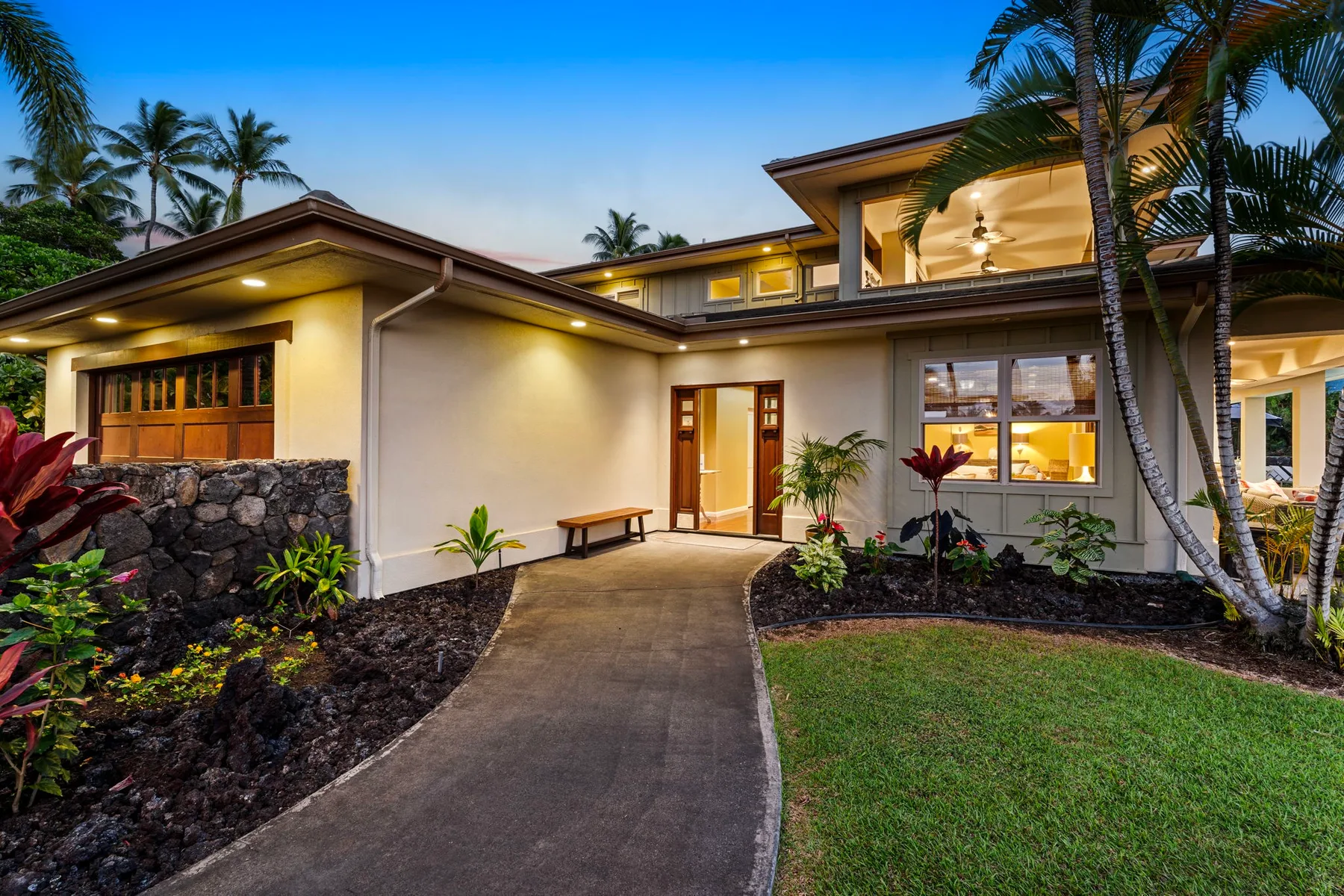 A modern house with a curved walkway leading to its illuminated entrance.
