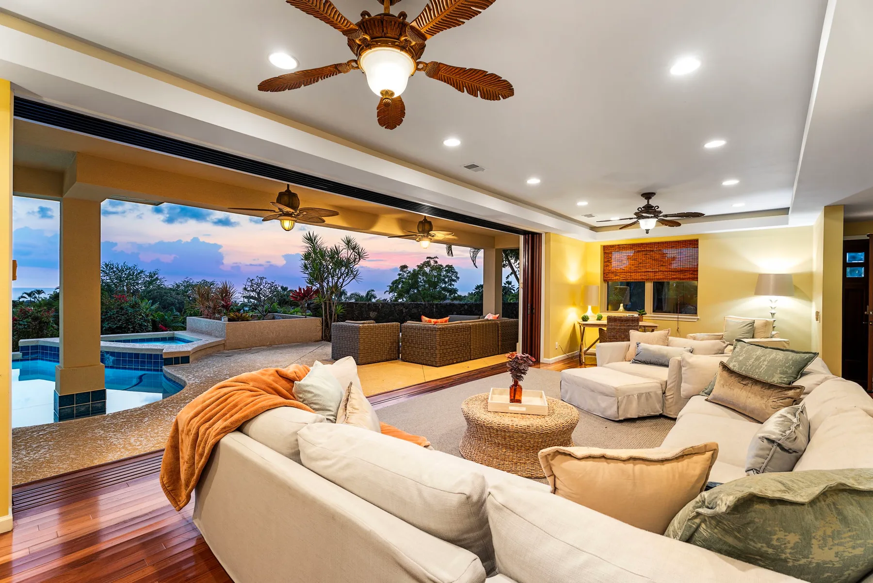 A spacious living room opens onto a covered patio with a pool and outdoor seating.