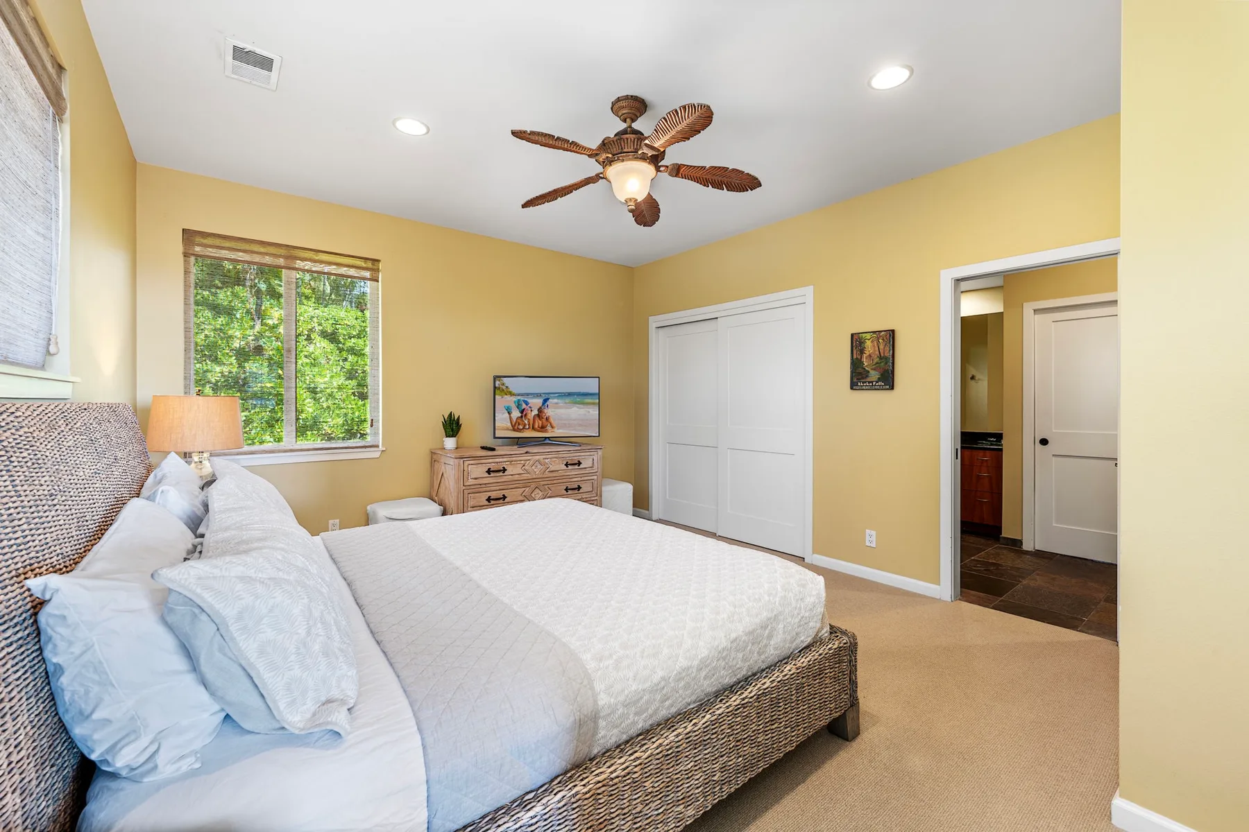 A bedroom with a bed, a window, and a ceiling fan.