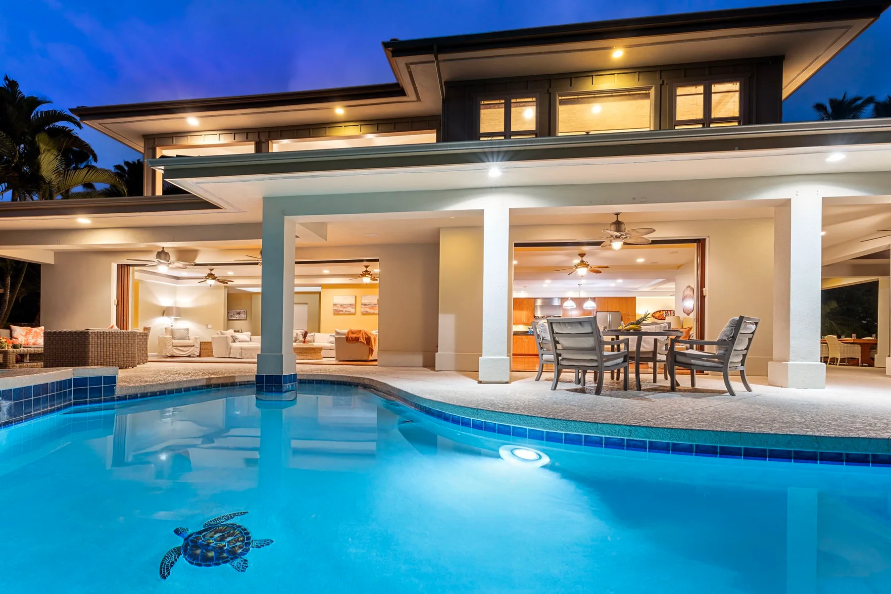 A modern house with a swimming pool and covered outdoor dining area at dusk.