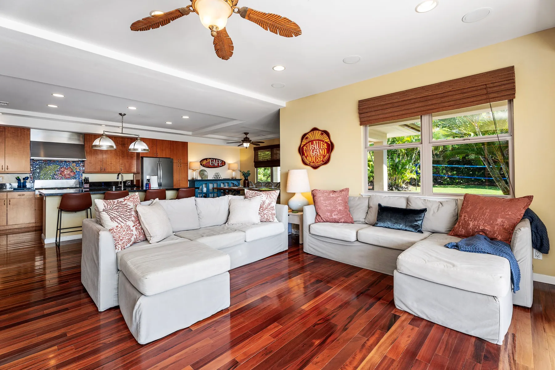 A bright living room with light-colored seating and an open kitchen.