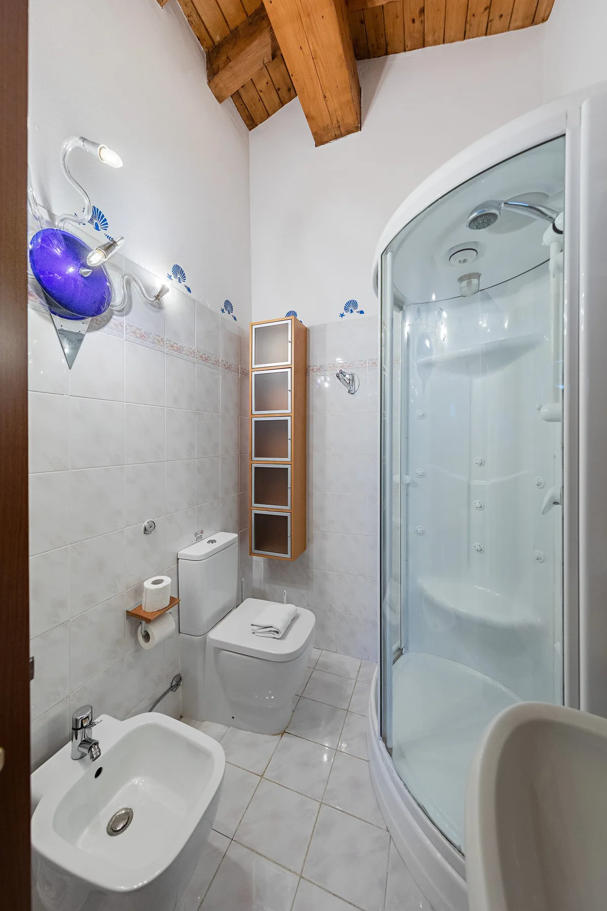 A tiled bathroom with a toilet, sink, and shower.