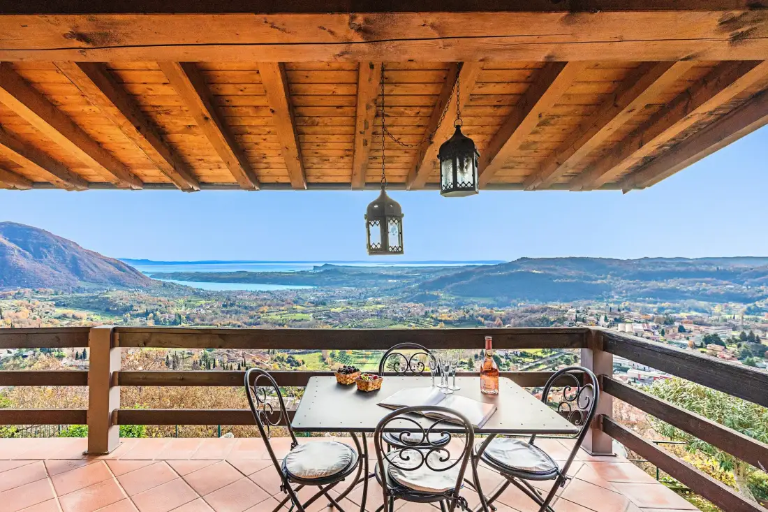 A covered terrace overlooks a broad valley, with outdoor seating and a table.