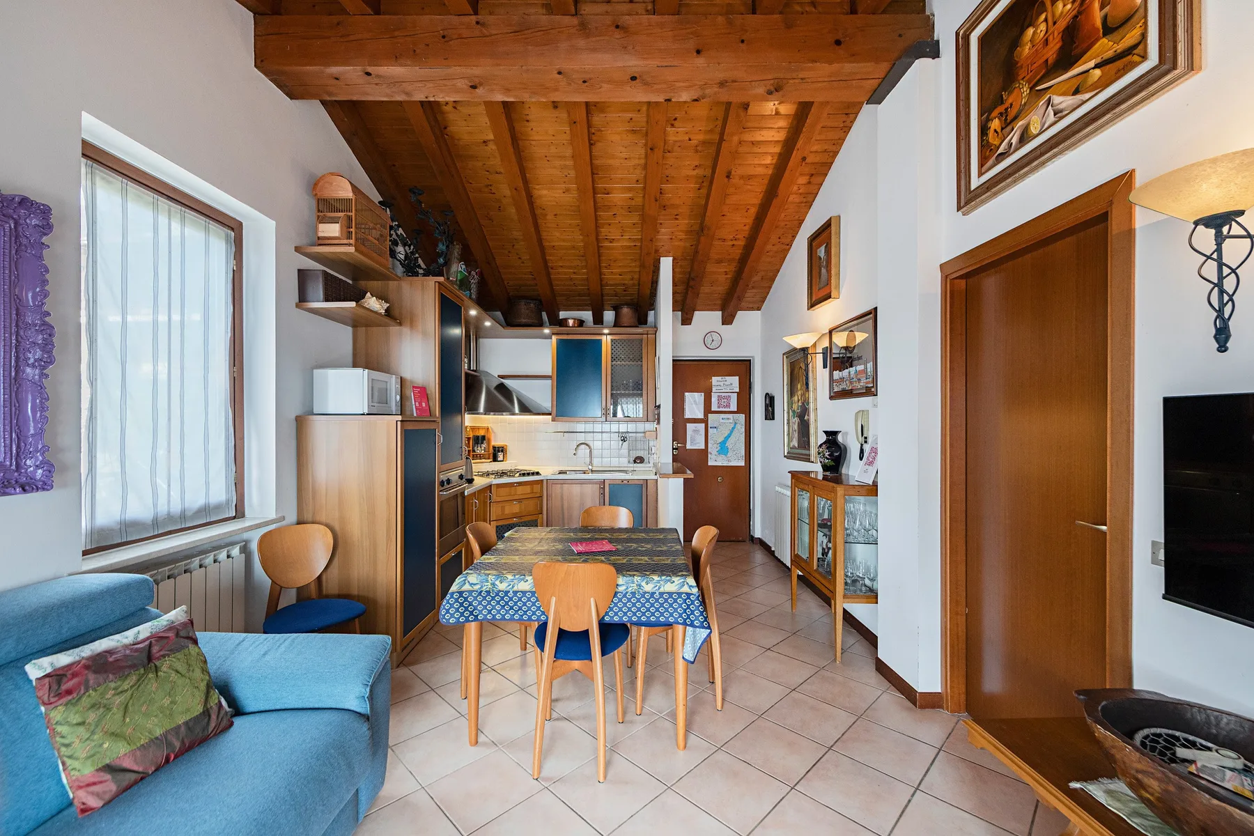 A compact living and dining area with a blue seating area and a wooden table.