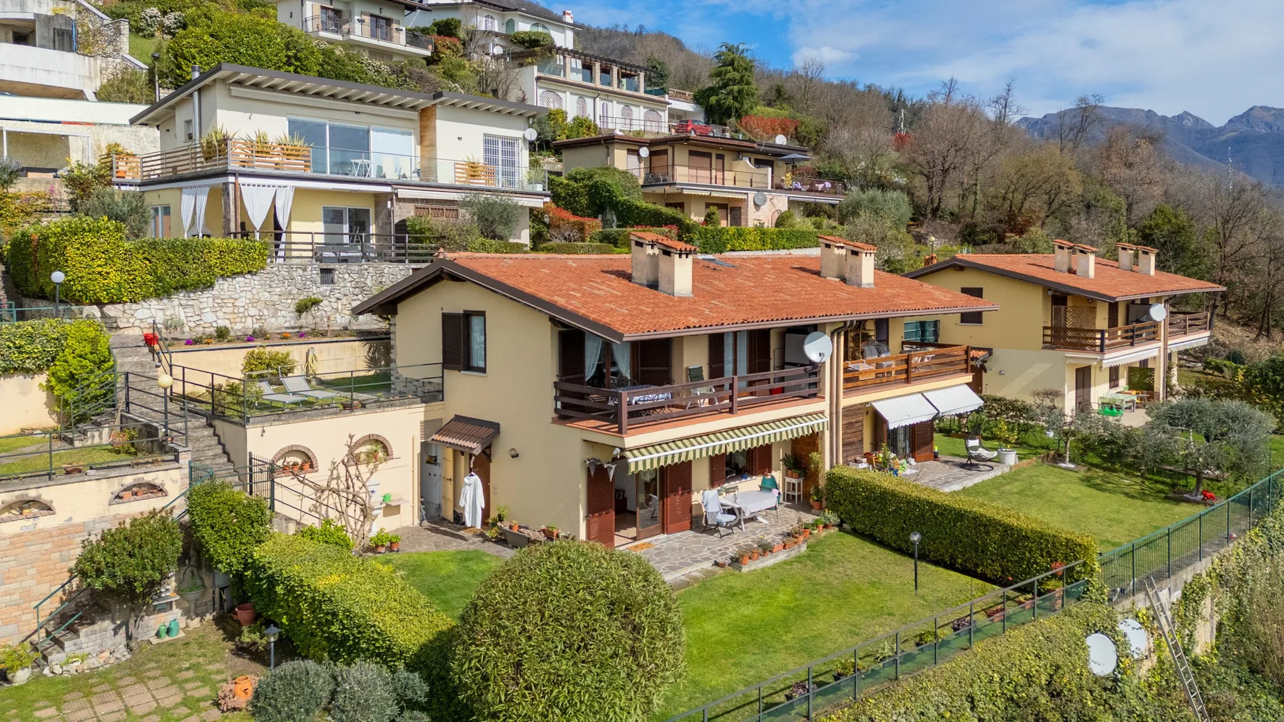 A hillside residential property with connected homes, balconies, and landscaped gardens.