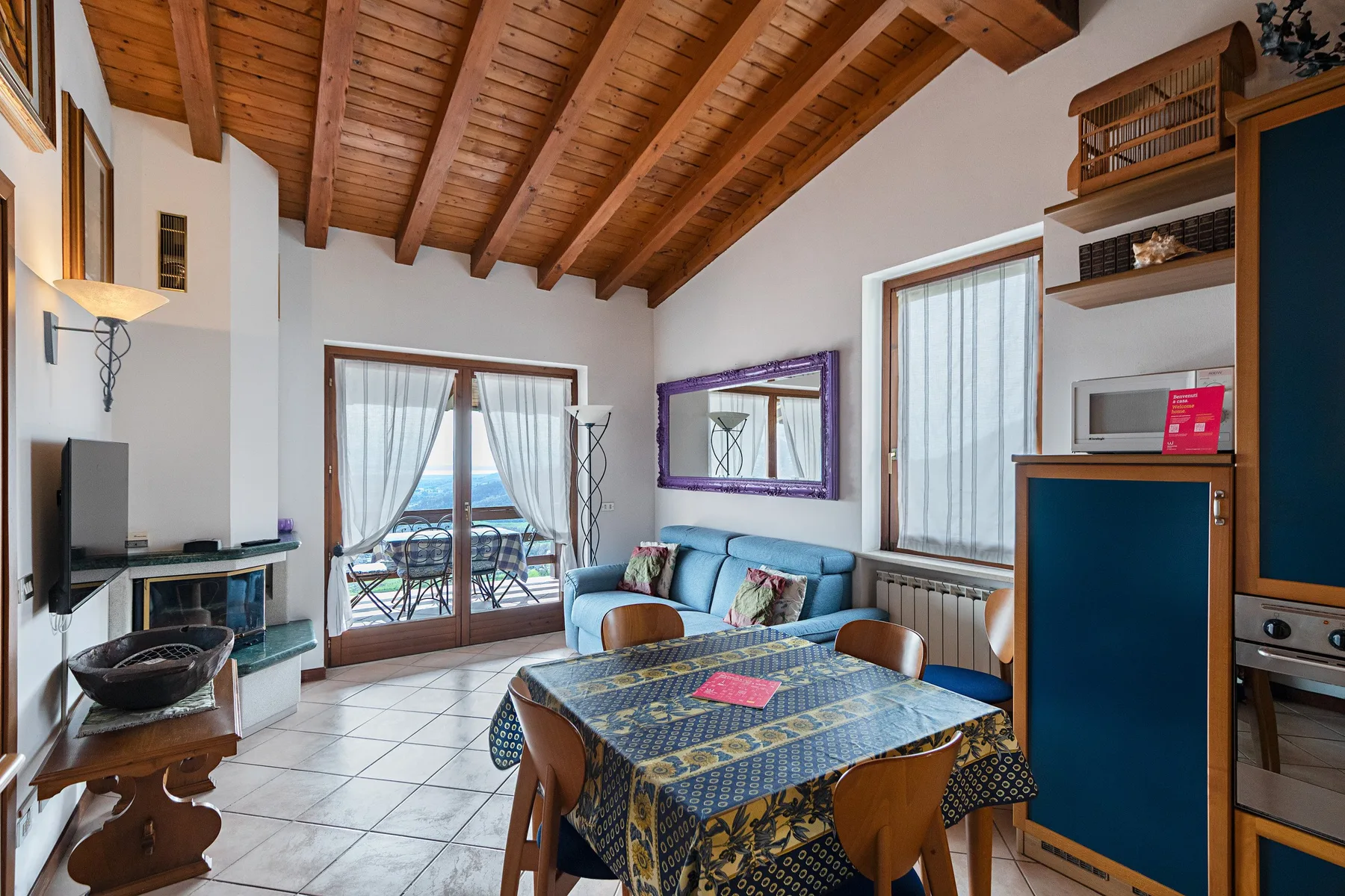 A living and dining area with a table, seating, and glass doors opening to a balcony.