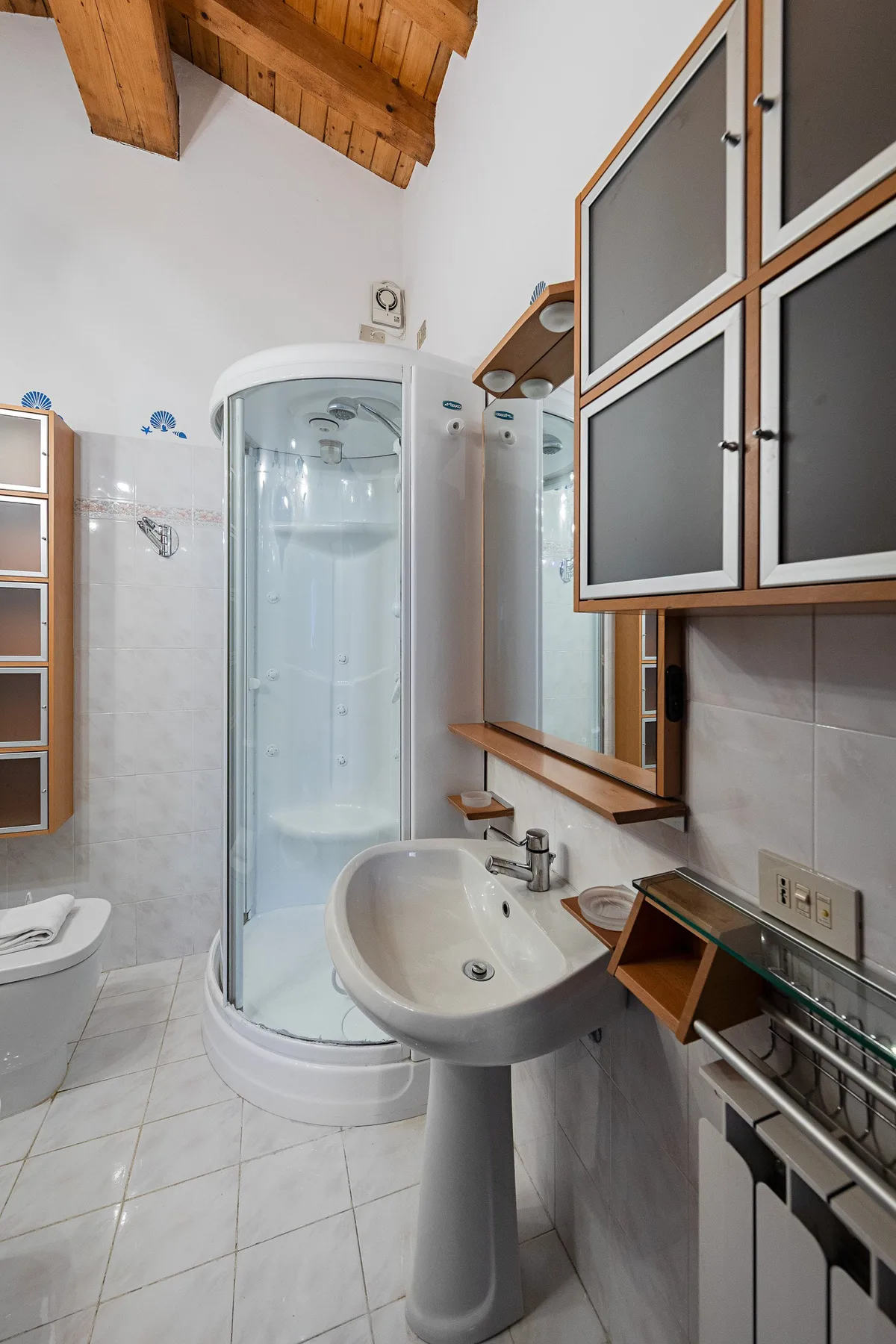A bathroom with a curved shower enclosure and a pedestal sink.