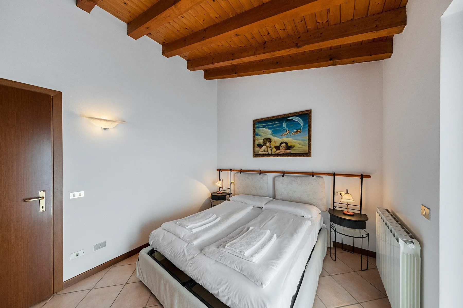 A bedroom with a double bed beneath exposed wooden ceiling beams.