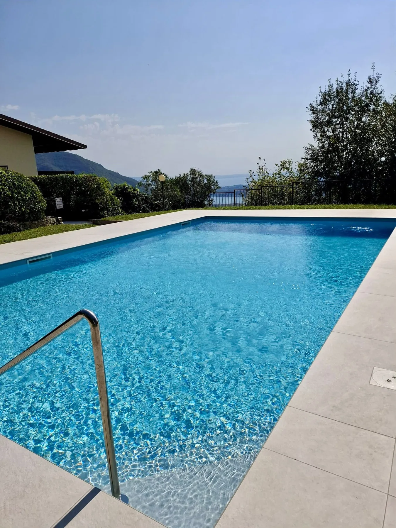 An outdoor swimming pool with blue water and a tiled deck.