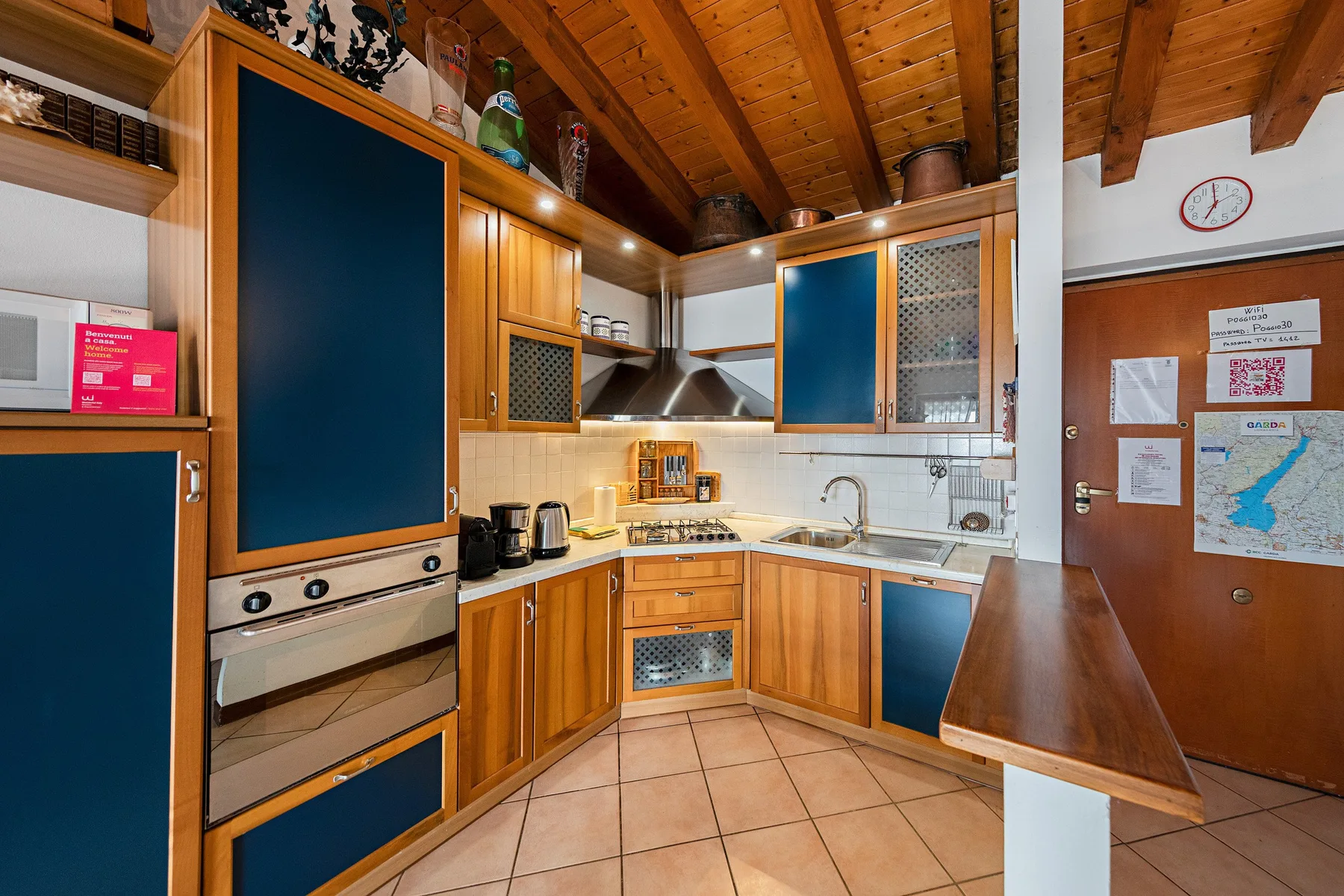 A compact kitchen with wooden cabinets, a cooktop, and a sloped wood ceiling.