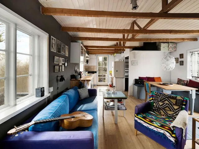 A living room with seating, a coffee table, and exposed ceiling beams.