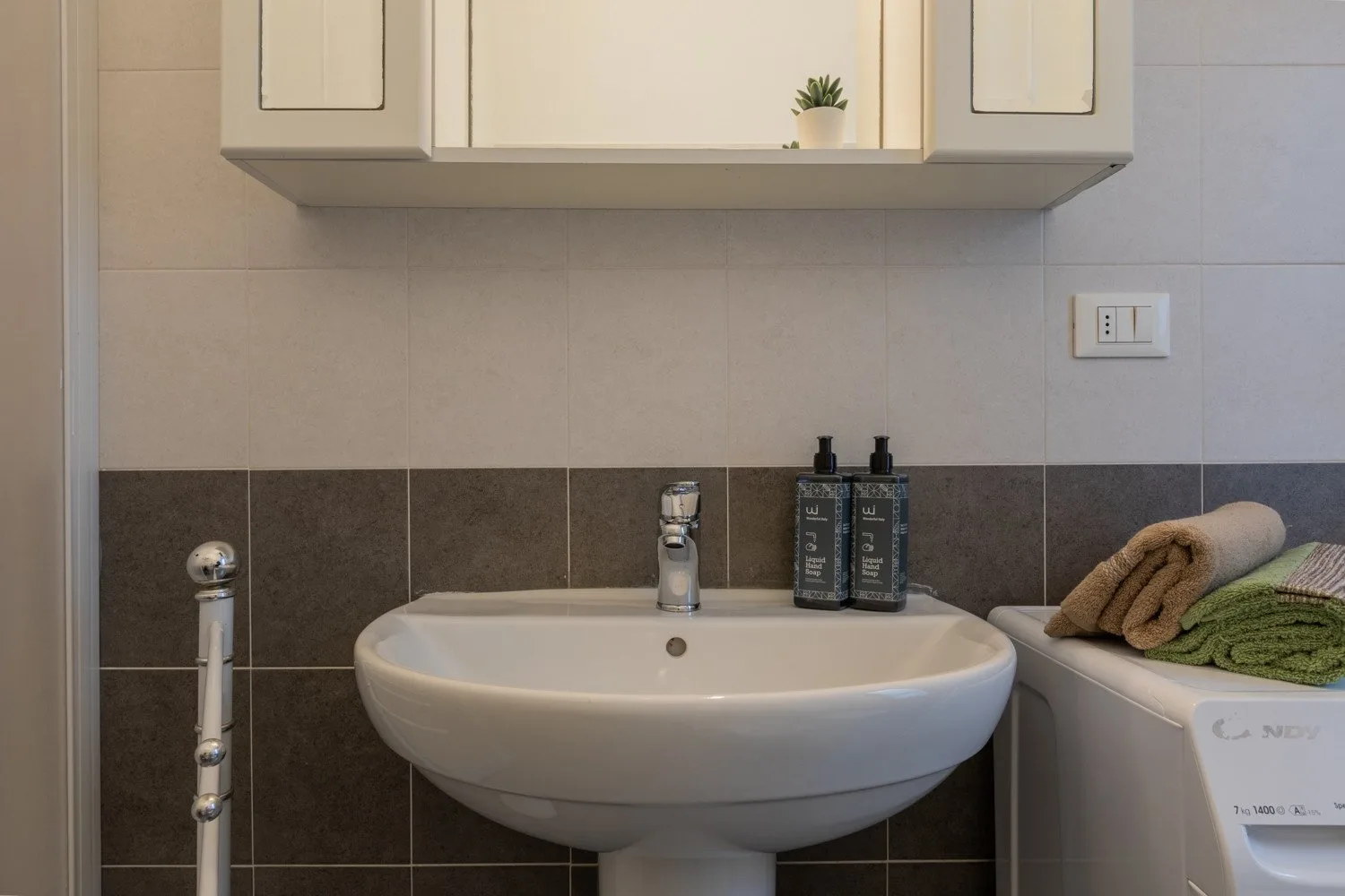 Un lavabo de baño está bajo un armario de pared, con toallas dobladas al lado.