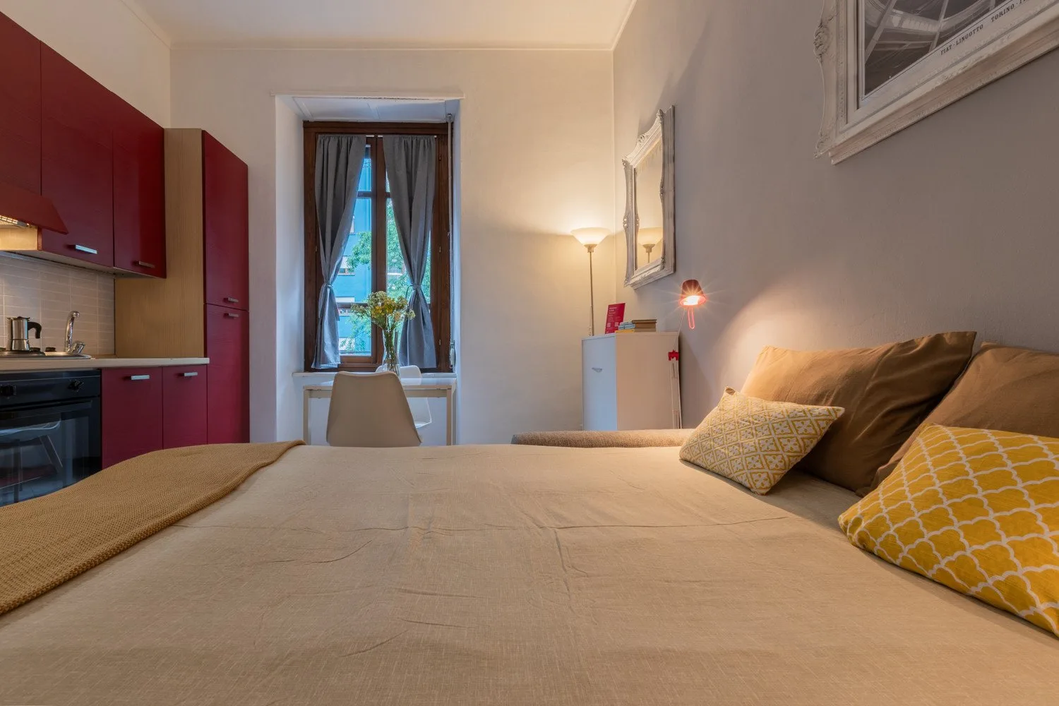 Un dormitorio con una cama grande, armarios de cocina rojos y una ventana con cortinas.