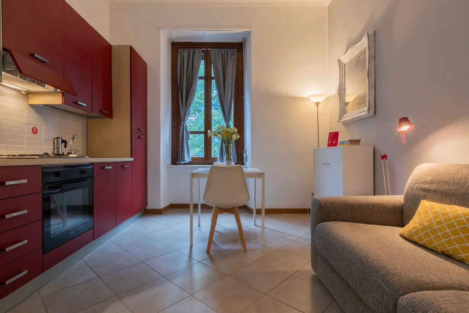 Una cocina compacta y zona de estar con una mesa junto a la ventana.