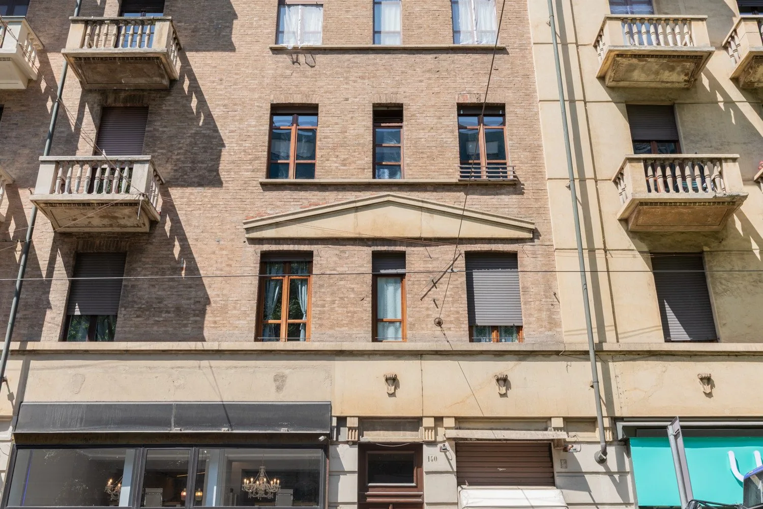 Fachada de un edificio a la calle, con ventanas, balcones y locales en la planta baja.