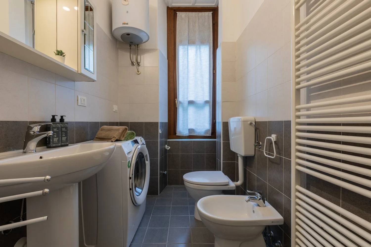 Un baño con azulejos, lavabo, inodoro, bidé y lavadora.