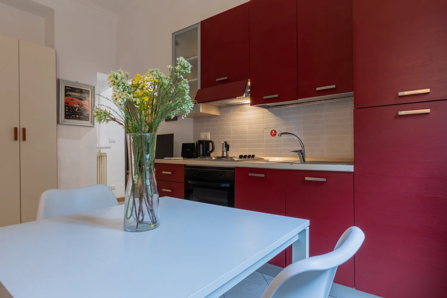 Una cocina con armarios rojos, una encimera y una mesa de comedor.