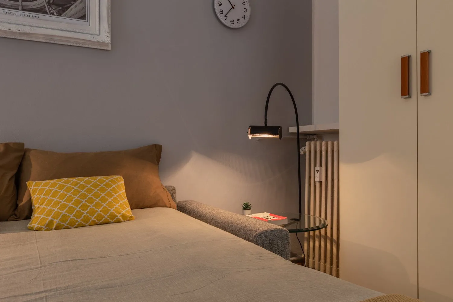 Un dormitorio con una cama, una mesita y una lámpara de pie.