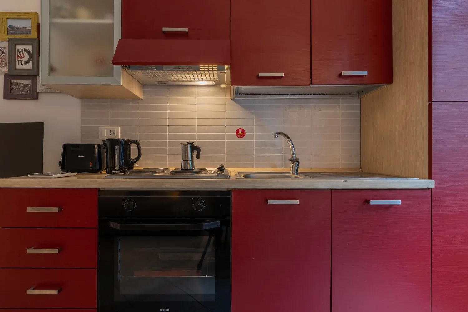 Una cocina con gabinetes rojos, una encimera y un fregadero.