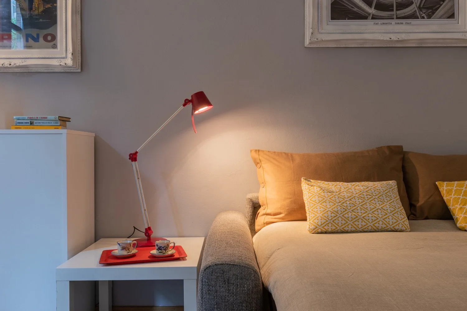 Una zona de dormitorio muestra una cama, una mesa auxiliar y una lámpara roja.