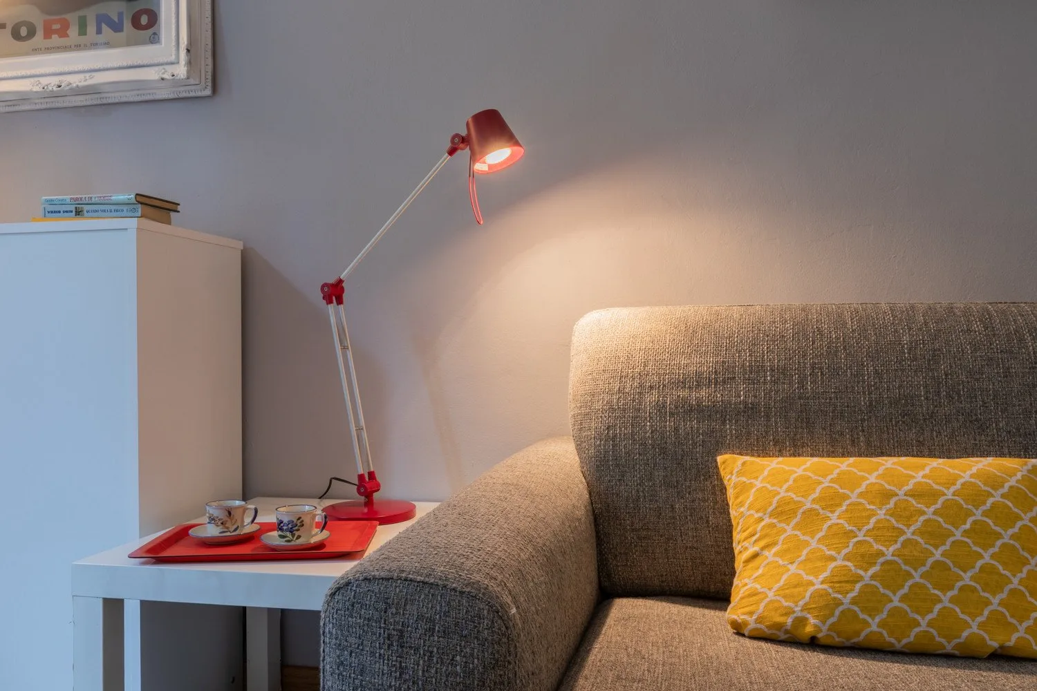 Una zona de estar con un cojín amarillo estampado y una lámpara de mesa encendida.
