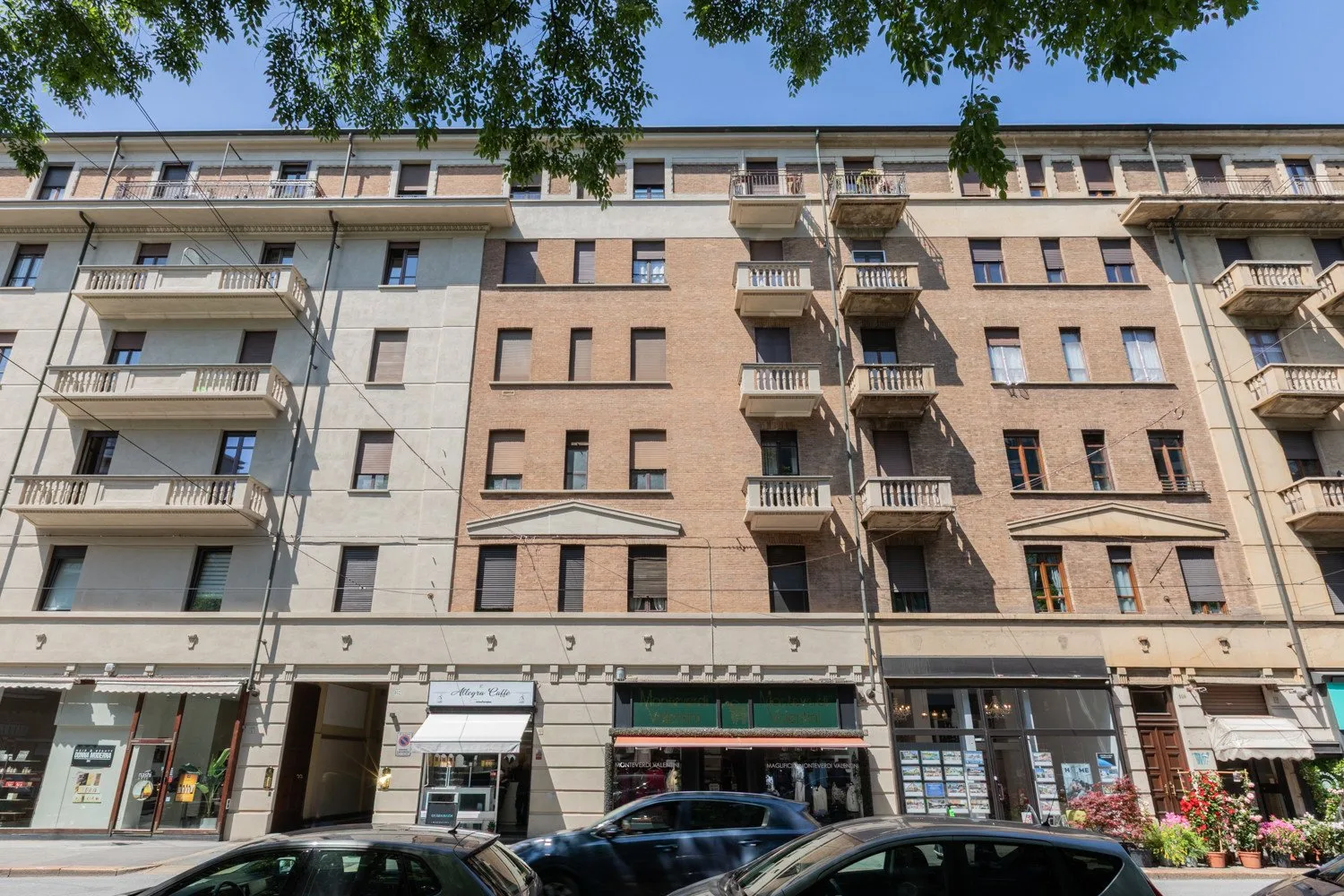 Un edificio de apartamentos de varios pisos con balcones y tiendas a nivel de calle.