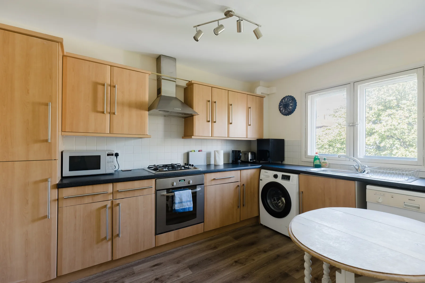 A bright kitchen with wooden cabinets, cooking appliances, and a window.