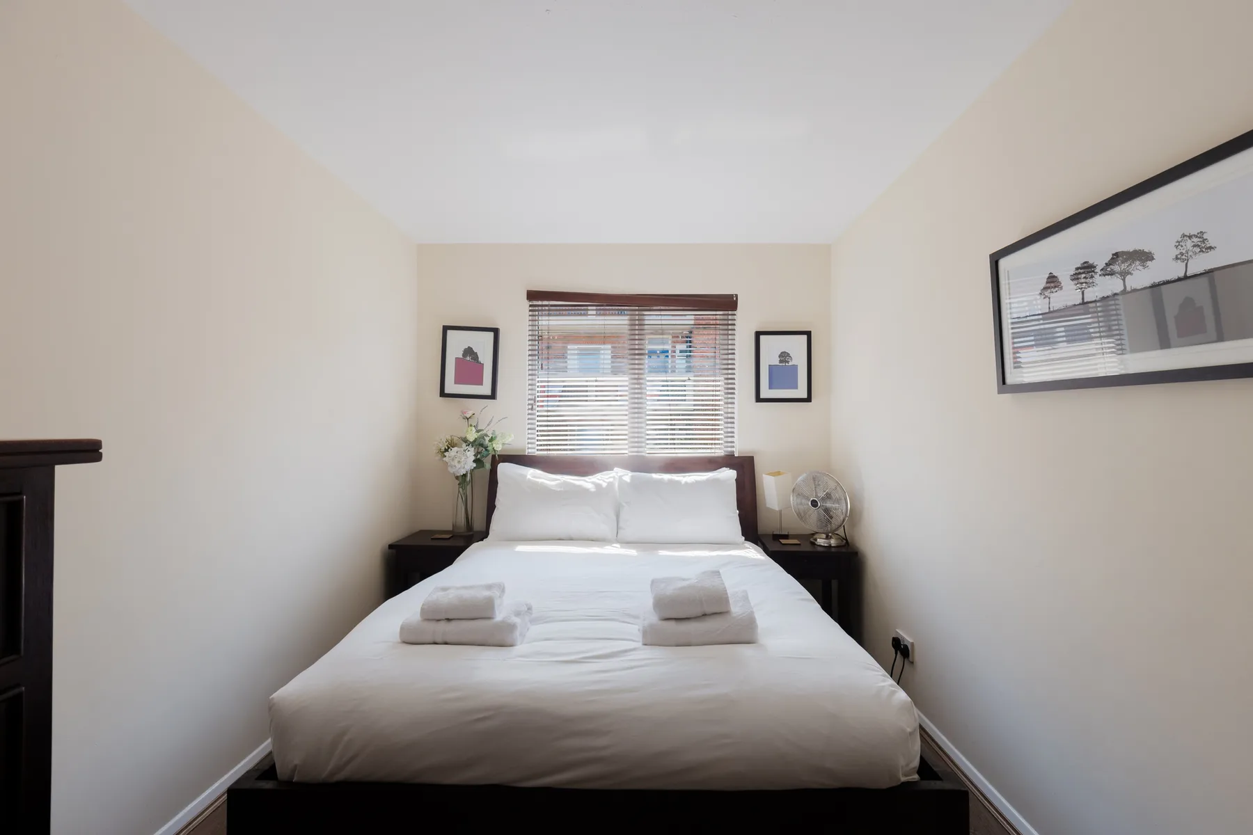 A bright bedroom with a neatly made bed beneath a window.