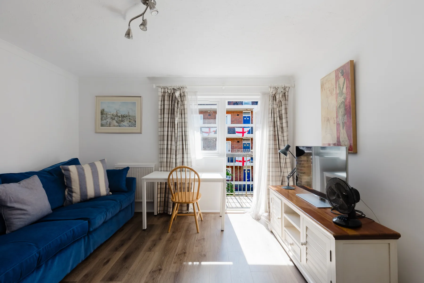 A living room with blue seating, a television, and a window.