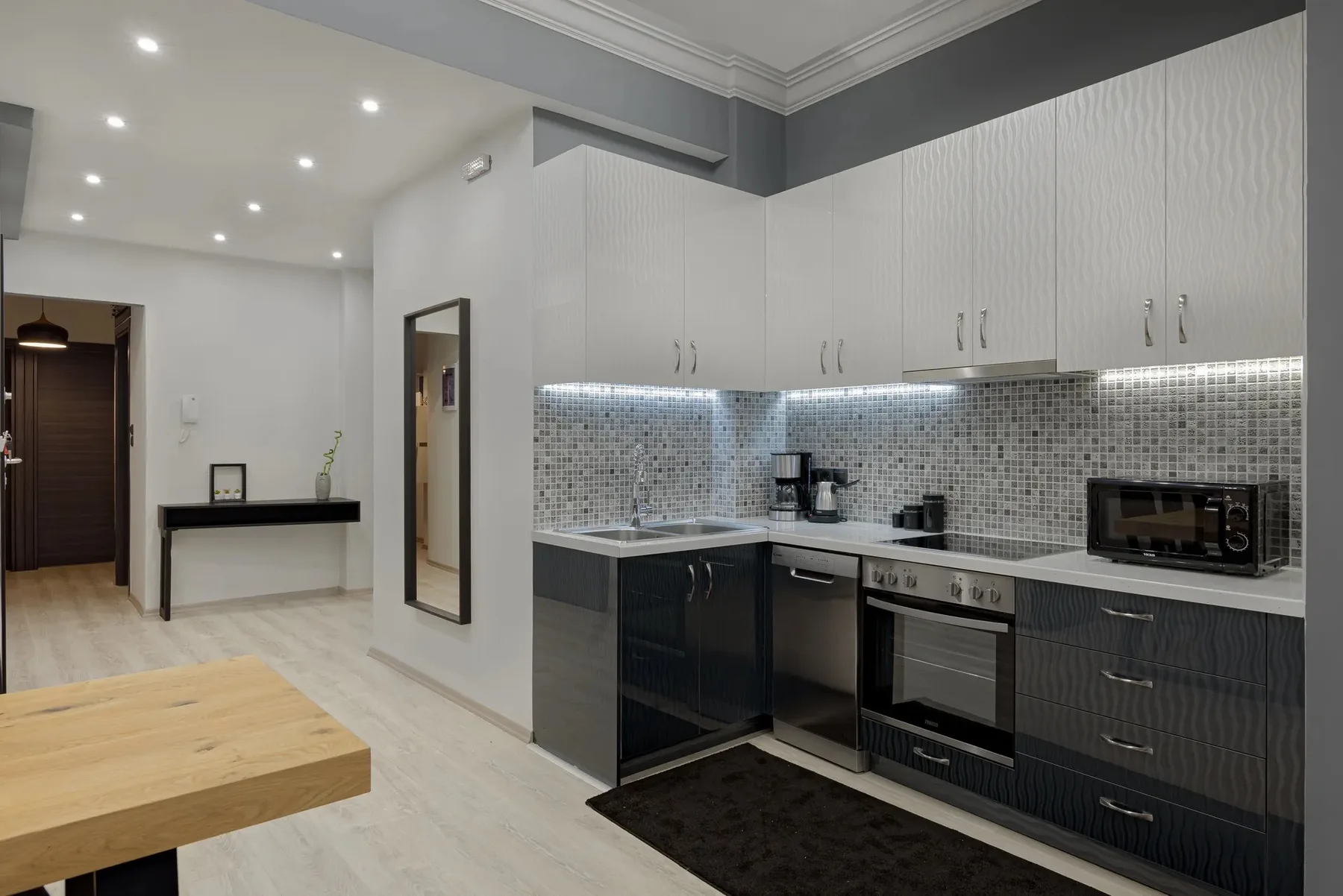 A modern kitchen with dark cabinets, a tiled backsplash, and a built-in oven.